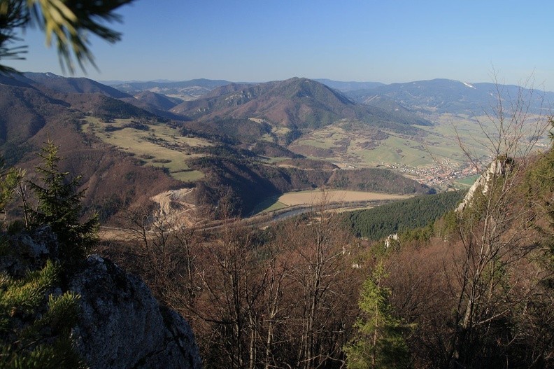 059-IMG 8059 -- Dla odmiany spoglądamy z grzbietu na północ: w dole toczy swe wody rzeka Orawa. Pozbawiony lasu grzbiet nad kamieniołomem
dźwiga się łagodnie na Magurkę (z mikroskopijną igiełką nadajnika). Zgrabne gniazdo górskie w środku kadru to Lysica (wierzchołek po prawej) z Sokolcem, wypuszczającym usiane skałami ramię. Za jęzorem lasu rozsypały się domy i domki Párnicy