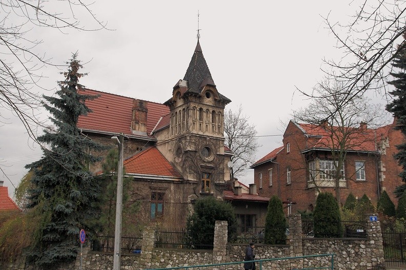 06-IMG 0112 -- Wyszliśmy na plac Lasoty. W 1896 roku (wtedy utworzono znajdujący się obok park) swą rezydencję wzniósł tu kolega po fachu Jerzego G., szanowany aptekarz i członek Rady Miasta Podgórza, Dyonizy Matula (<a href="http://podgorze.pl/wp-content/uploads/Dyonizy_Matula_web.jpg" target="_blank">LINK</a>). Pierwszy właściciel pasjonował się architekturą – pozostawił po sobie w piwnicy obszerny zbiór czasopism z tej dziedziny. Autorem utrzymanej w duchu historyzmu koncepcji budynku był Józef Kryłowski (projektant m.in. wiaduktu nad ul. Dietla). Zewnętrzną ozdobę tej "twierdzy" stanowi efektowna wieża, zaś wewnątrz można oglądać wysokie na 3,6 m pokoje, elegancką balustradę i natrysk z wodą podgrzewaną w piecu węglowym. Zachowały się pamiątki
po Matuli: apteczne butelki, drzewiec sztandaru Polskiego Towarzystwa Gimnastycznego "Sokół", jak również szabla paradna członka Rady Miejskiej. Ciekawe są dwukondygnacyjne podziemia: posiadają łukowe sklepienia, ze ścian wystaje wapienna skała. W trakcie wojny
w domu stacjonowali niemieccy żołnierze; dziś zwie się Willa Mira. Obok stoi pochodząca z początku XX wieku Willa Julia – nosząca imię żony Wojciecha Bednarskiego, który w niej mieszkał