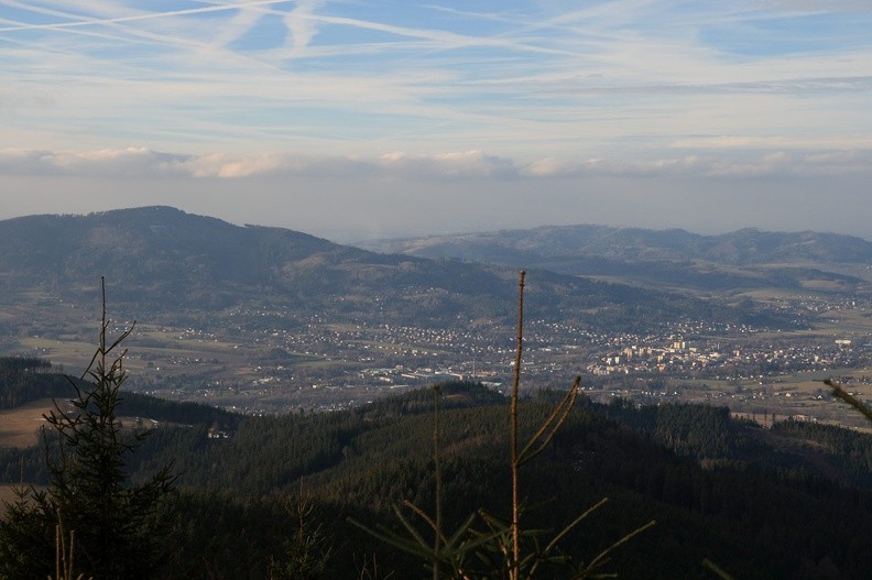 23-IMG 0820 -- Na zachodzie leży Frydlant nad Ostrawicą, za nim mamy (sprawiający wrażenie nie lada góry) masyw Ondřejníka. Kolejny, nieewidentny, ciemnawy plan zajmuje jednostka pogórza zwana Metylovickou pahorkatinou. Jej najwyższym (widocznym na lewo od czubka "badyla") wzniesieniem jest Kozlovická hora. Z niebem graniczą Palkovické hůrky. Ciekawostka: widzimy tu Babią Górę, która po czesku zwie się Babí hora i ma zawrotną wysokość 619 m n.p.m. Usytuowana jest mniej więcej w centralnej części Palkovických hůrek