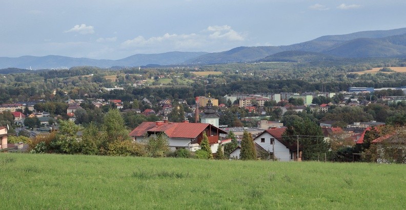 08-IMG 0604 -- Zwracamy się na wschód. Spośród dachów i drzew wystaje wieża skoczowskiego kościoła pod wezwaniem świętych apostołów Piotra
i Pawła (środek zdjęcia). Łagodnym przybojem oddycha Pogórze Śląskie. Najbliższy nieco wypuklejszy akcent po prawej to Górka
(474 m n.p.m., nad Grodźcem) u podnóża Beskidu Śląskiego. W dali, z lewej, mamy blady wał Beskidu Małego