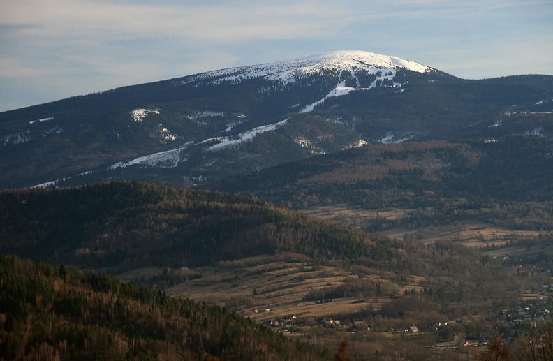 105-IMG 6205 -- Równoległe nitki miedz znaczą dźwigający się leniwie grzbiet Kiczory. Dominantę krajobrazu stanowi Pilsko,
którego dolna część udekorowana jest białą wstęgą stoków narciarskich na Szlakówce